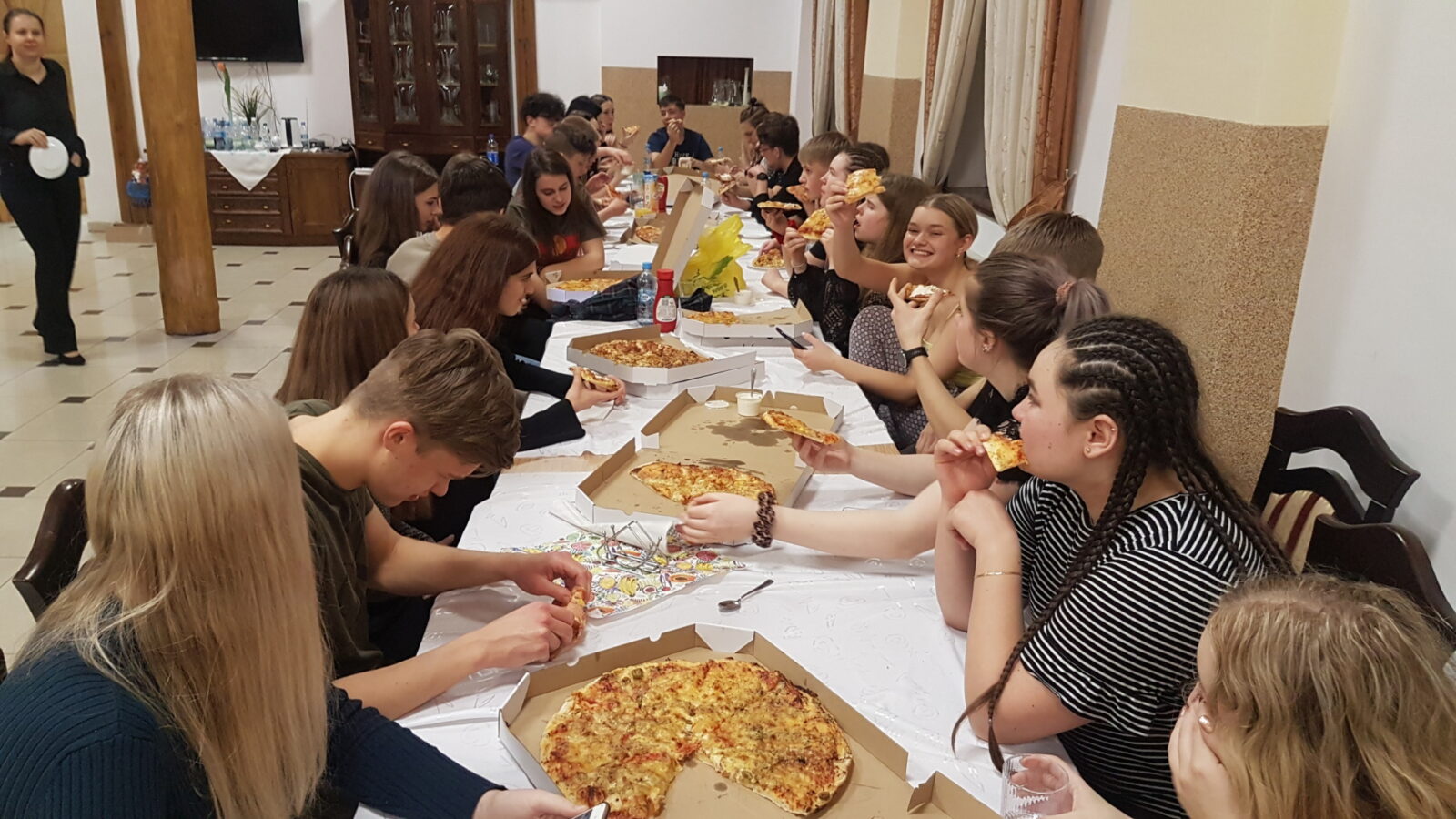 Ungdommer som spiser pizza ved et langbort