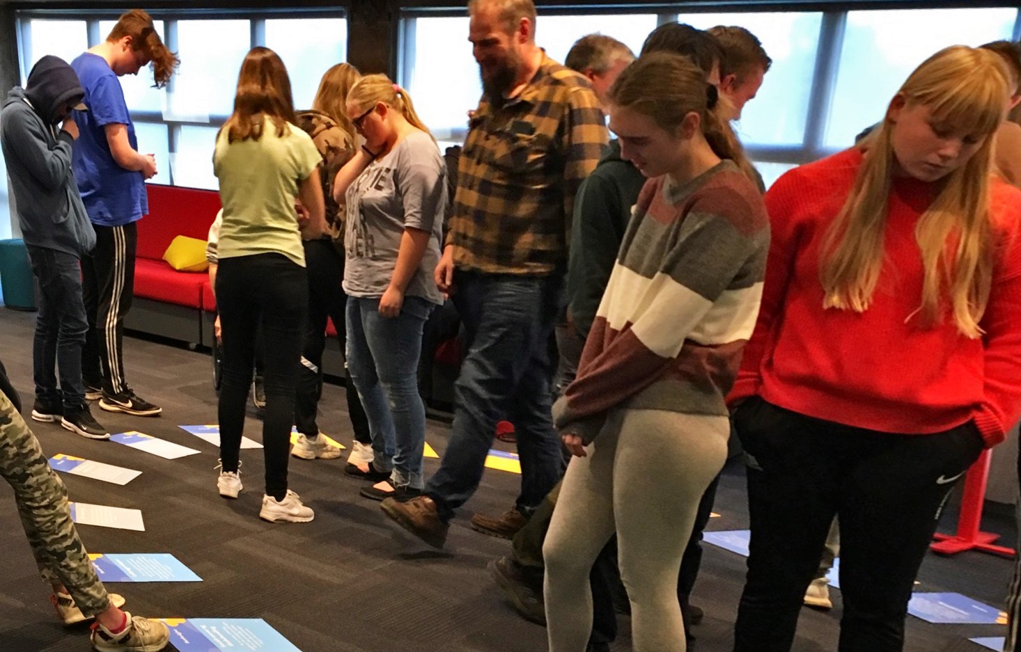 Ungdommer deltar på en workshop og kikker på printet materiell som ligger på gulvet
