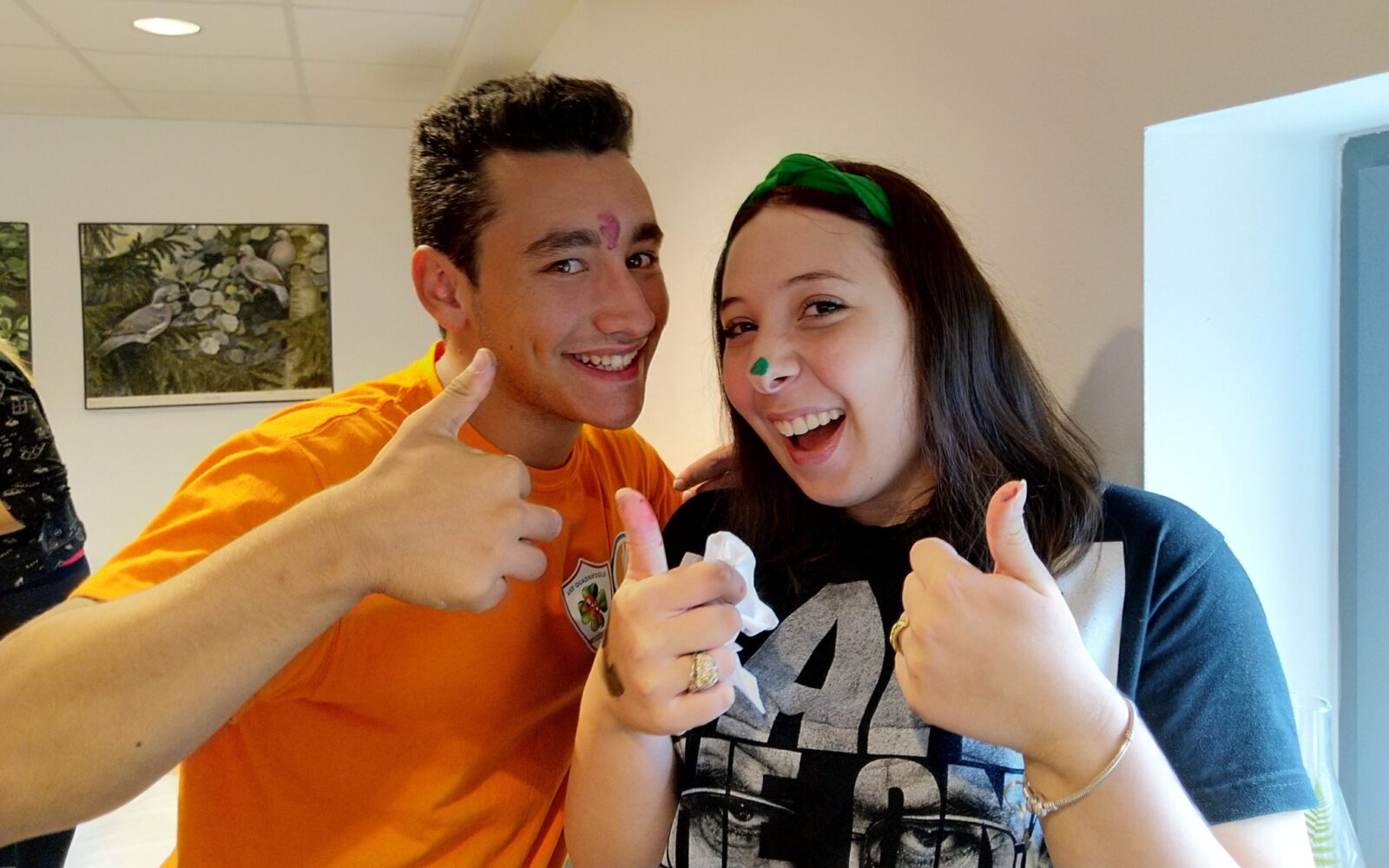En ung mann og en ung kvinne holder opp tommelen og smiler