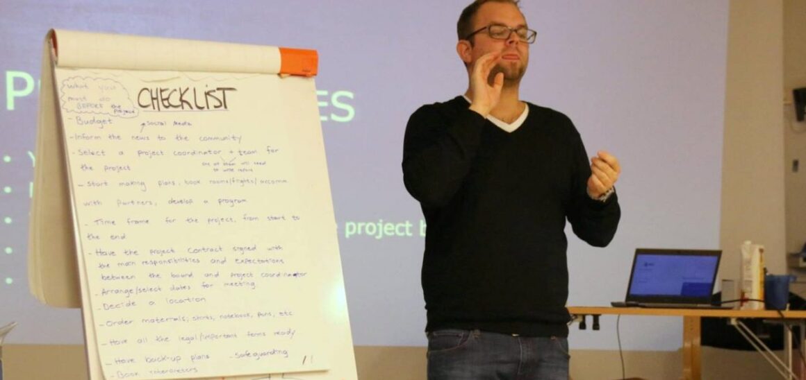 En ungdomsarbeider presenterer en sjekkliste på en flipchart
