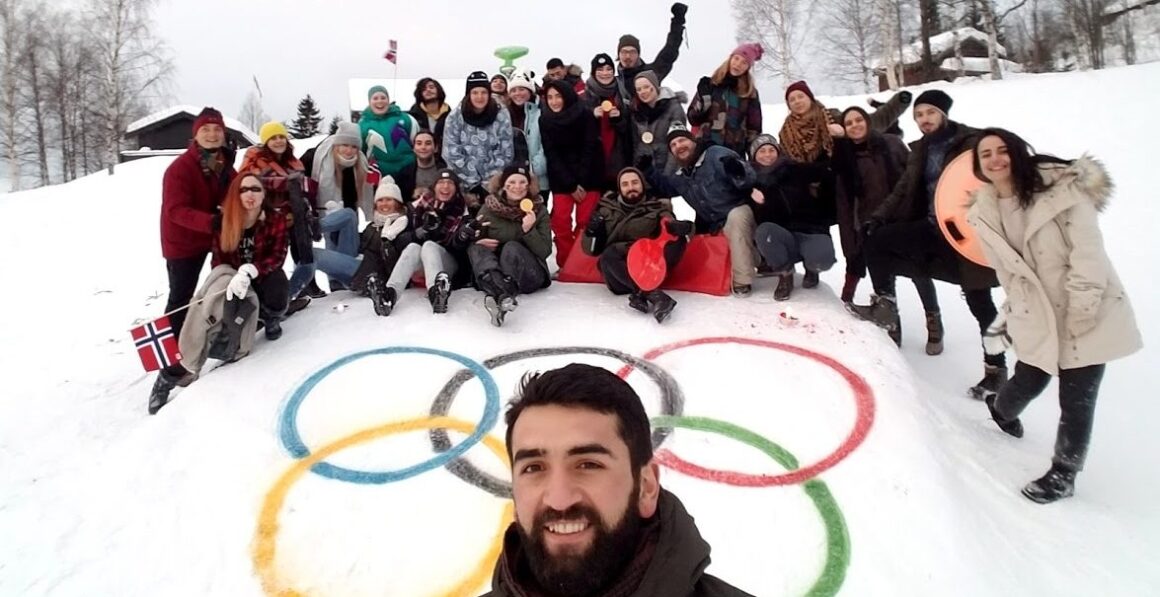 En gruppe deltakere poserer foran de olympiske ringer malt opp i snøen