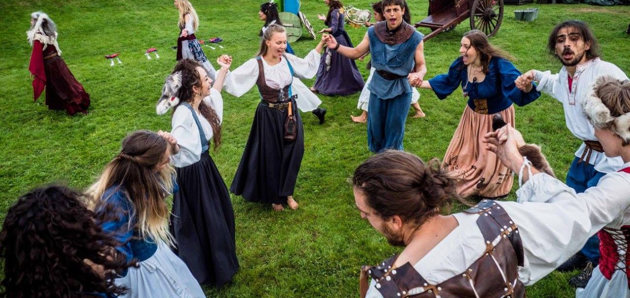 Artister i middelalderkostymer som danser i sirkel