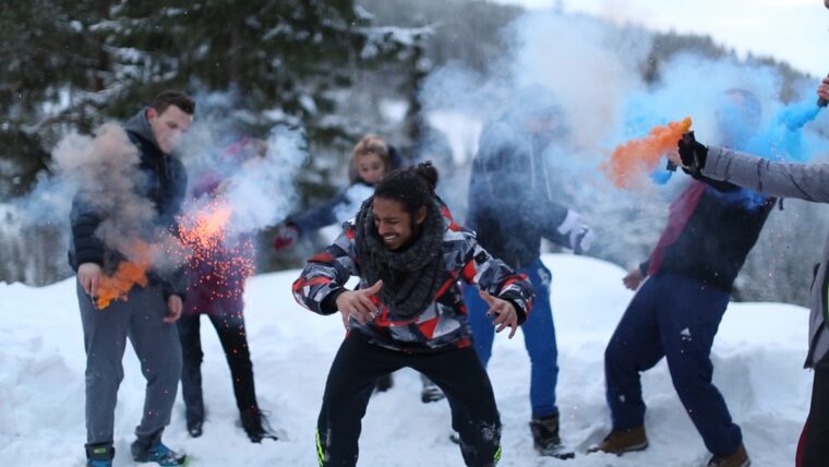 Ungdommer i snøen leker med fargerike røykbomber