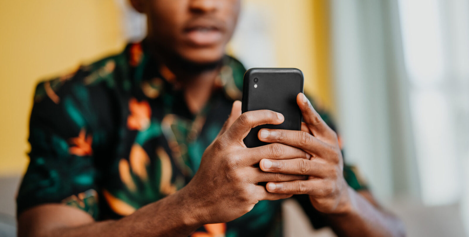 Bilde av en ung mann som holder en telefon