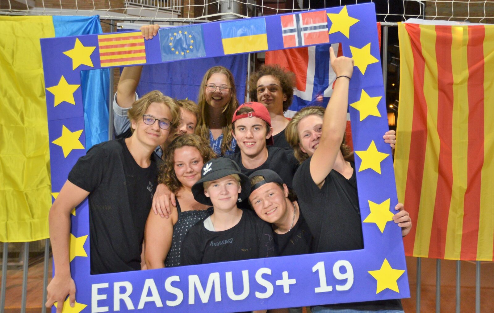 9 ungdommer poserer inni en stor blå ramme med flagg, stjerner og Erasmus+ 19.