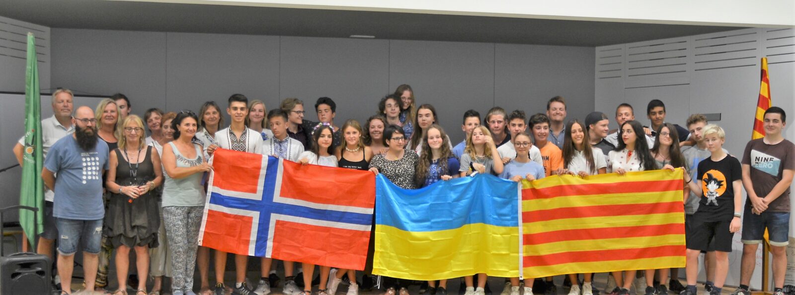 Ungdommer på gruppeutveksling poserer med store flagg fra Norge, Ukraina og Katalonia i Spania