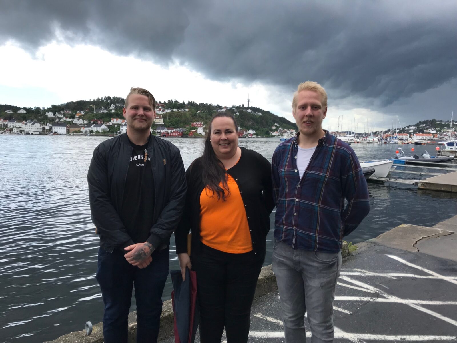Bilde av to unge frivillige og en ansatt fra Nav ved en brygge.