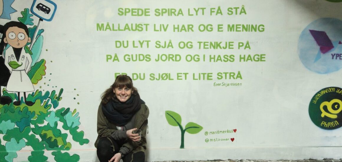 En ung kvinne poserer foran et dikt malt i en undergrunn