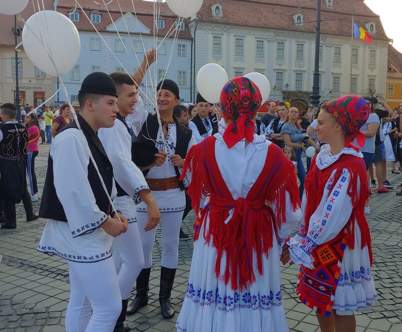 Tre menn og to kvinner i rumenske nasjonaldrakter. Mennene holder på ballonger.