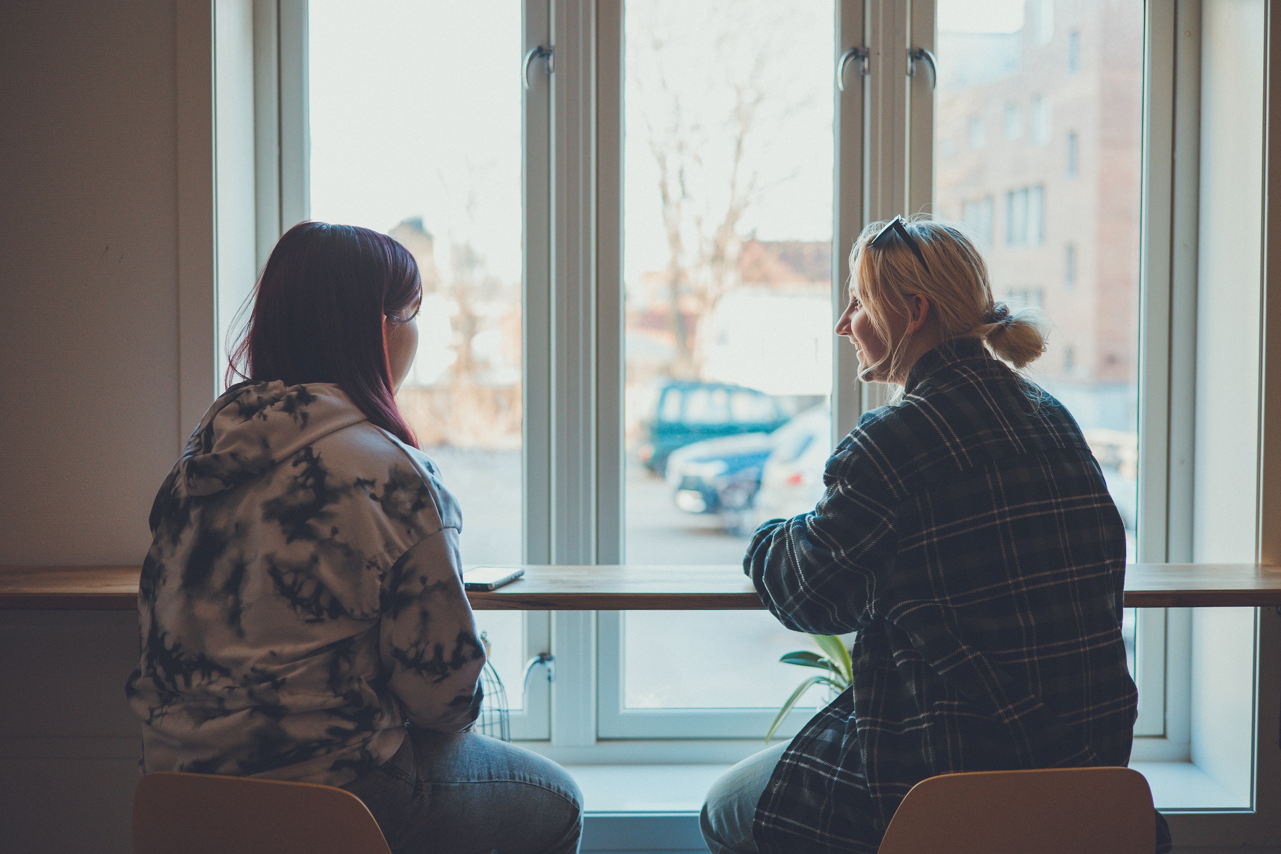 To unge mennesker sitter på en kafe og ser ut av vinduet