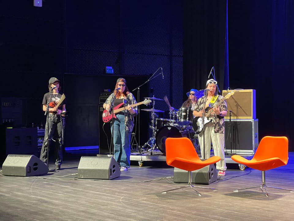 tre ungdommer holder konsert på en scene