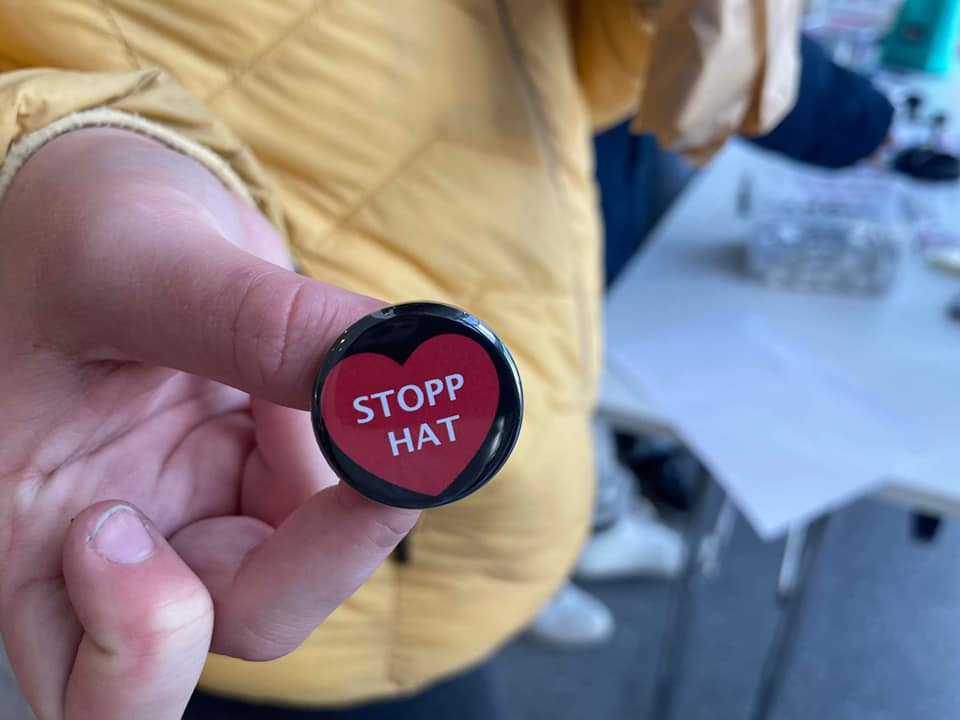 en hånd viser fram en button hvor det står