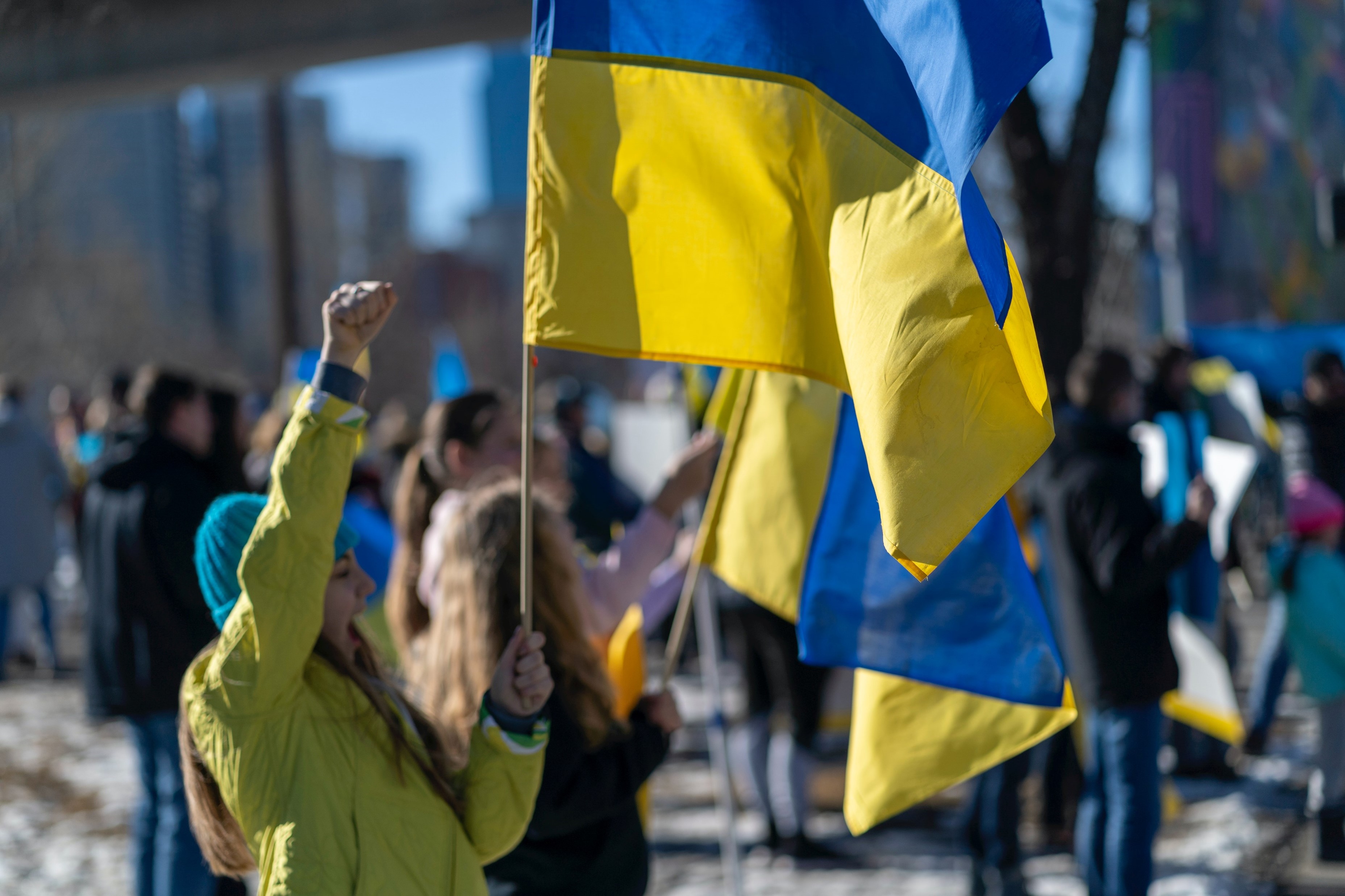 En kvinne hever neven i været mens hun holder et blått og gult ukrainsk flagg