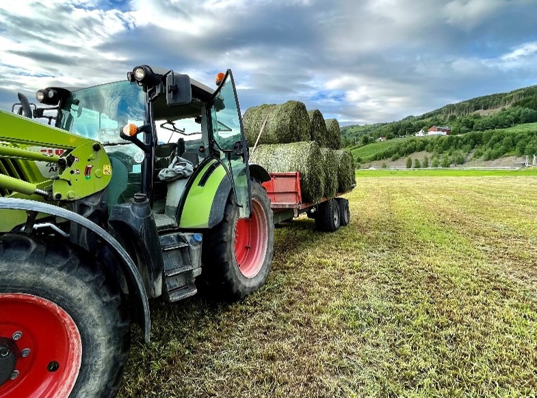 Bilde av en traktor som samler inn høyballer