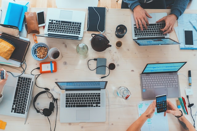 folk sitter rundt et bord med hver sin laptop