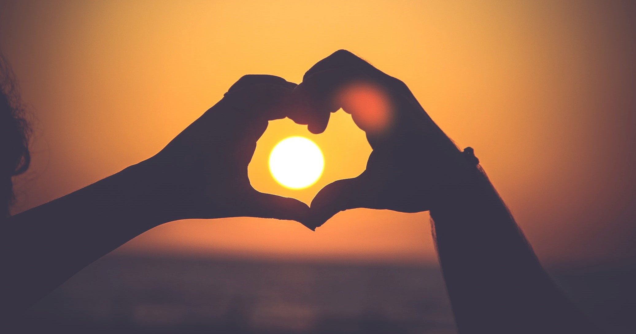To hender former et hjerte foran en solnedgang