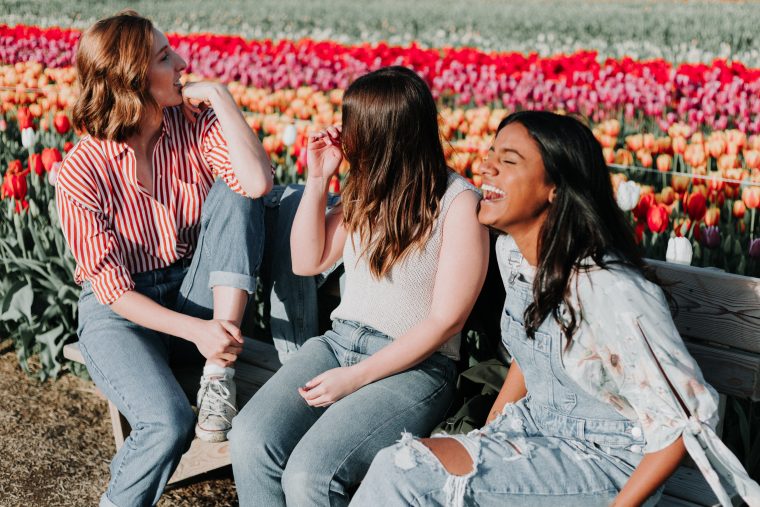 Tre unge kvinner i en blomstereng