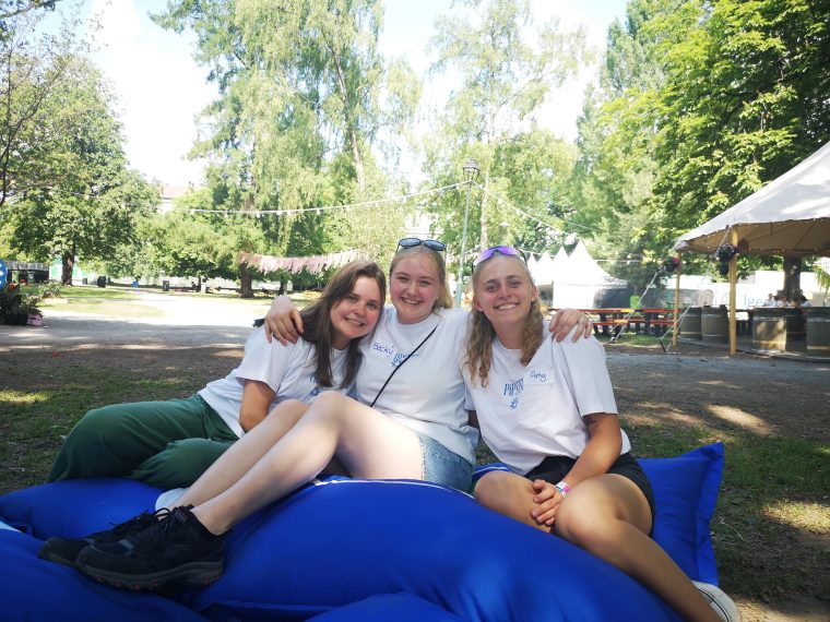 Tre unge jenter sitter i en saccosekk i en park.