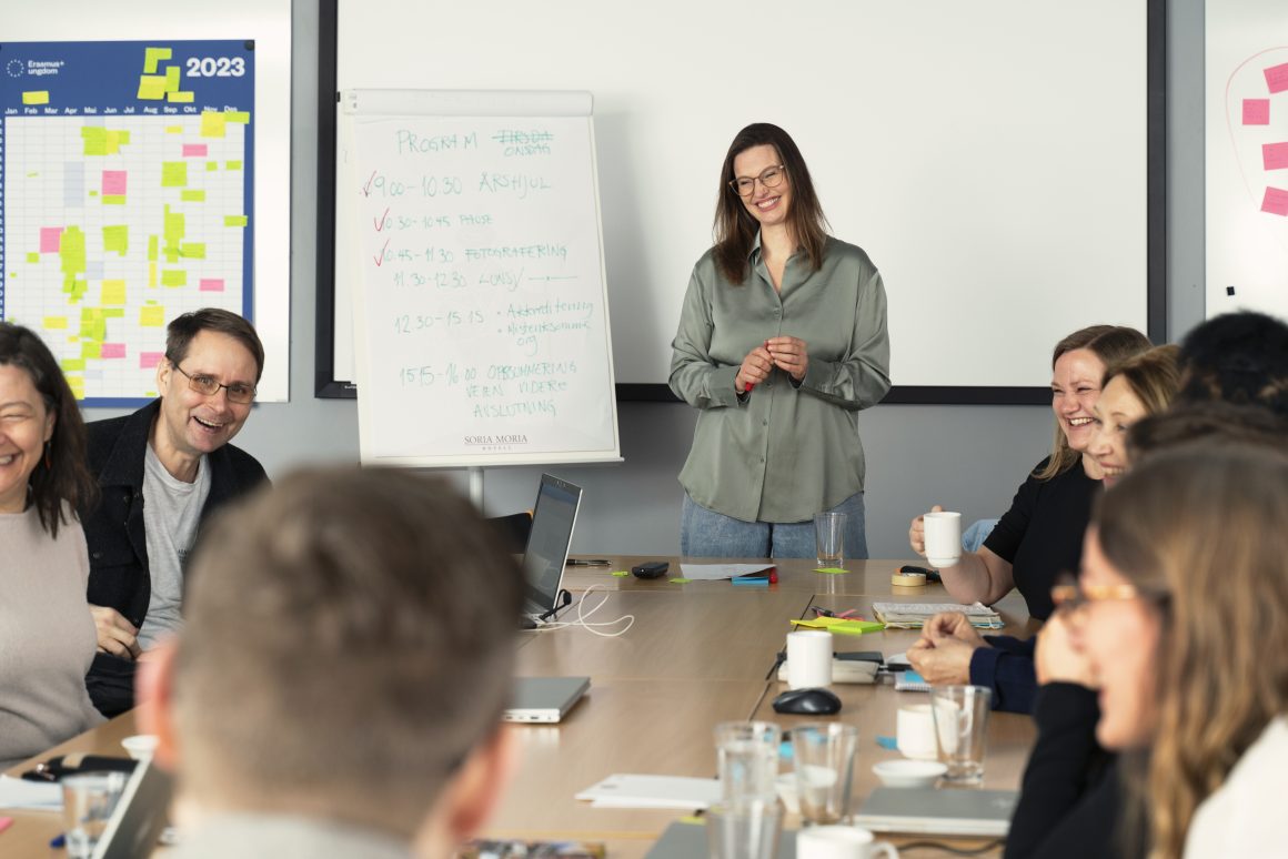 En gruppe kolleger sitter rundt et bord og ler