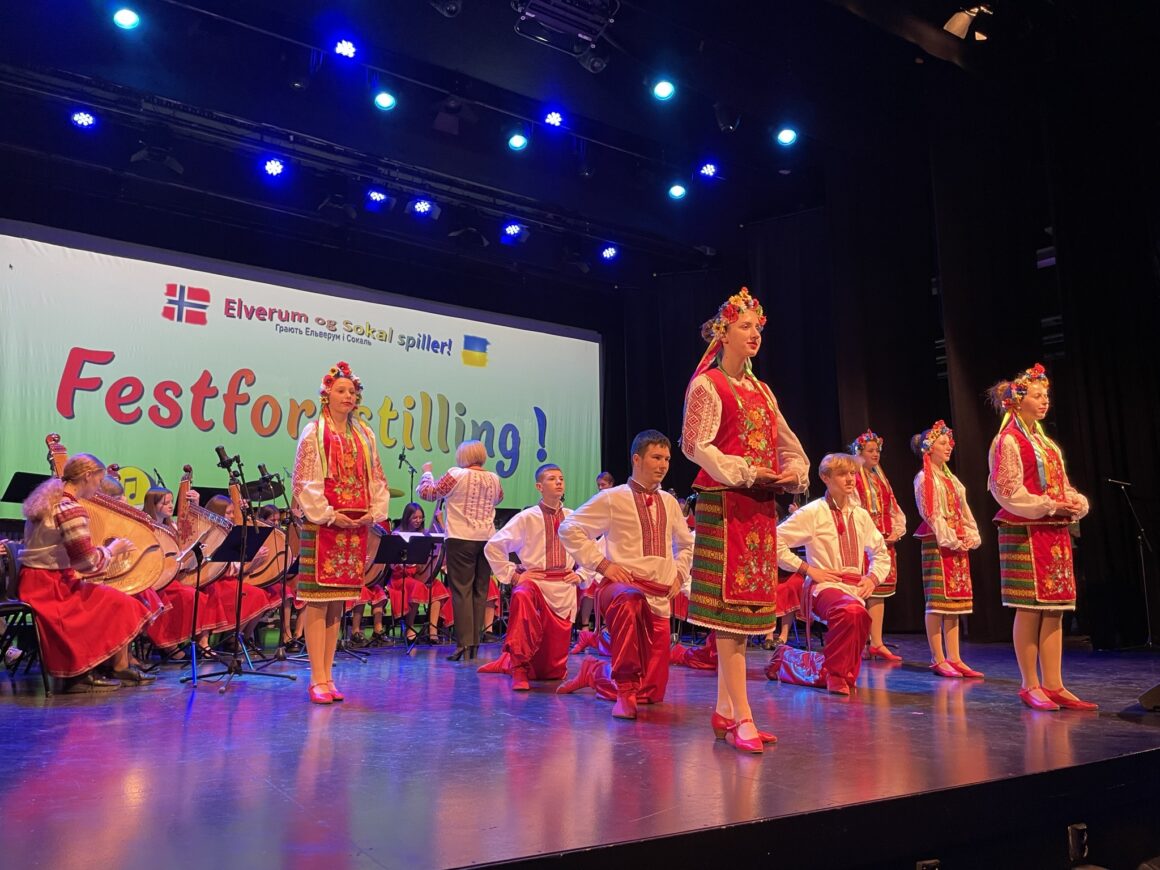 Flere dansere på en scene, med ukrainsk folkedrakt på. Musikere sitter i bakgrunnen.